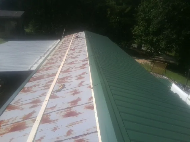 Old rusted panels beside newly installed green metal roofing — Wind Damage Roof Repair by Roofing Brothers in Dodge