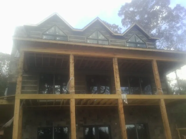 Dormers and porch framing on a large log home under construction — Roof Coating work by our crew in Dodge