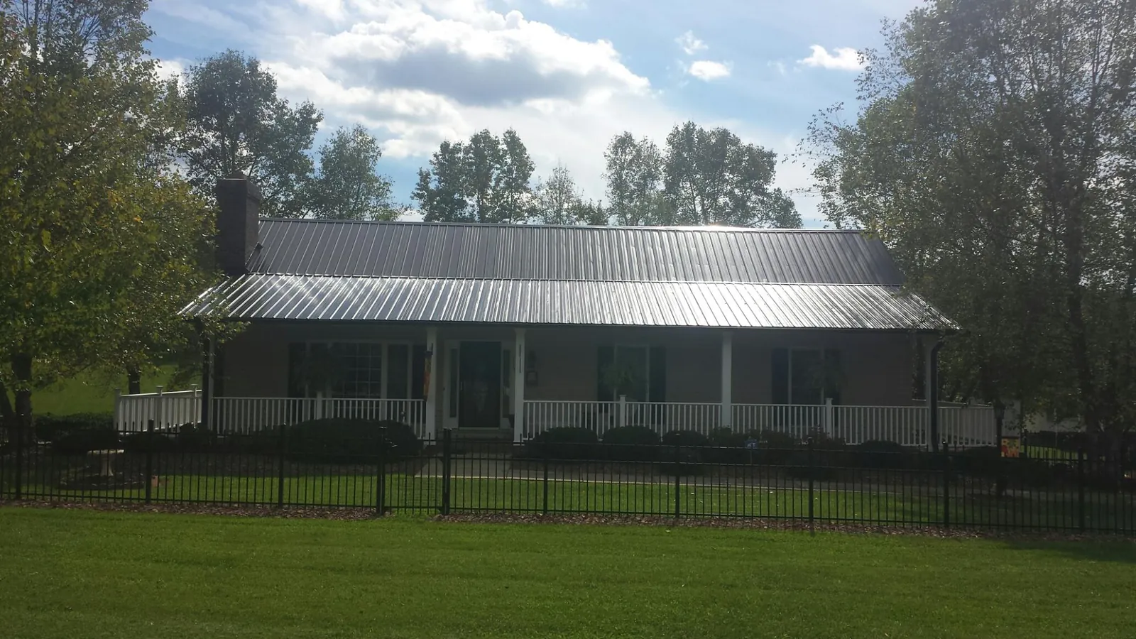 Gray metal roof on a brick ranch with a full width front porch — Gutter Guard Installation work by our crew in Dodge